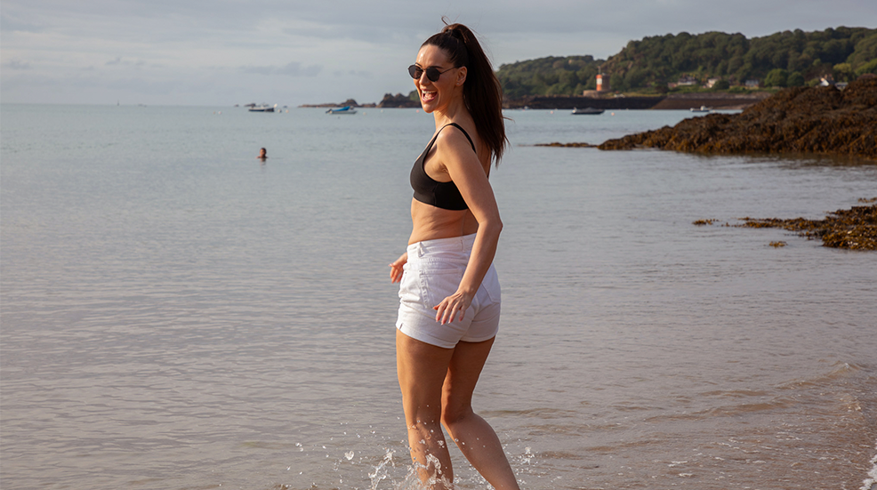 Woman frolics in the sea on a beach in Jersey